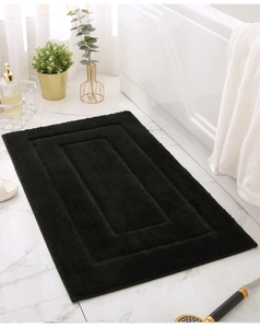 Detail of black rectangular bathroom mat with dense pile and textured geometric pattern
