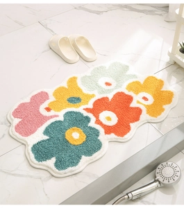 Detail of colorful flower-shaped bath mat with thick flocked texture on marble floor