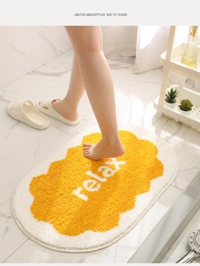 Detail showing the absorbent tufted texture of the yellow and white egg-shaped bath mat