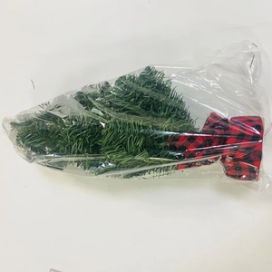 Mini tabletop artificial Christmas tree with red buffalo plaid base in plastic bag packaging