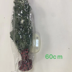 60cm mini Christmas tree with red plaid base being weighed on a digital scale