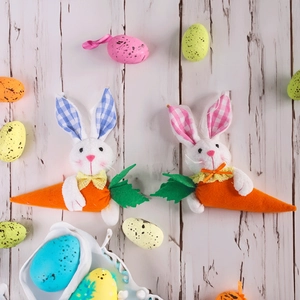 Detail of plush Easter bunnies with lace bows and felt carrots on wooden background