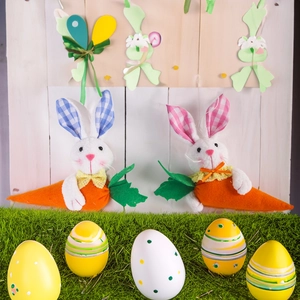 Easter plush bunny couple with orange carrots and colorful eggs on green grass scene