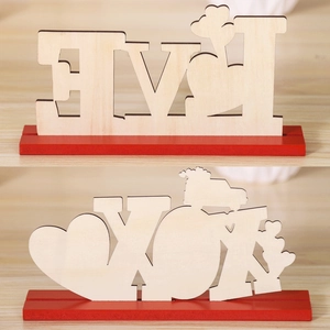 Detail of laser-cut LOVE and YOU wooden table signs with red base for festive decor