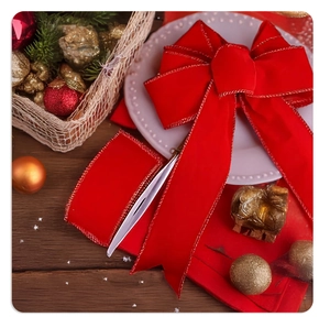 Detail of red velvet Christmas bow with gold trim on festive table setting