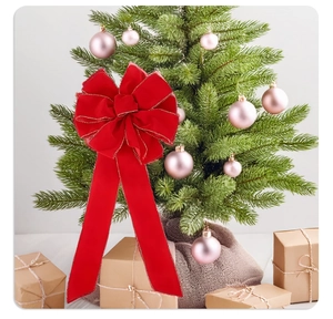 Festive red velvet Christmas bow with gold trim hanging on a decorated tree branch