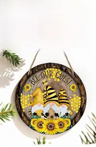 Detail of round wooden sign with Bee Our Guest slogan and gnome sunflower motifs
