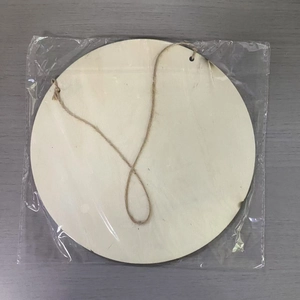 Close-up of blank round wooden hanging sign with jute rope in plastic packaging