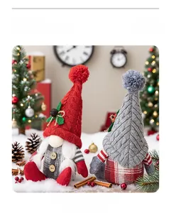 Close-up of knit Christmas gnomes with fuzzy hats and holly leaves on festive snow background
