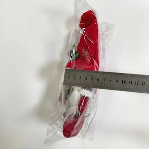 Weihnachtswichtel in Schutzverpackung mit Lineal zur Größenmessung auf weißem Grund