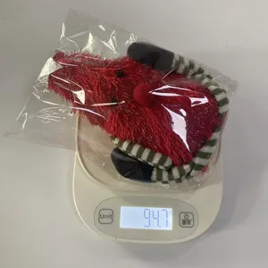 Close-up of a plush red Christmas doll with striped legs weighing 94.7g on a scale