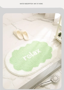 Detail showing plush cream-colored absorbent bath mat with relax clouds on marble tiles