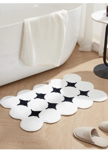 Close-up of white cloud-shaped plush rug with black star patterns on wooden floor