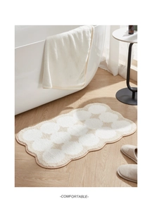 Irregular wavy bath mat with white dots on soft cream velvet in a cozy bathroom setting