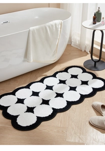 Detailed view of plush black and white polka dot bath mat with wavy scalloped edges