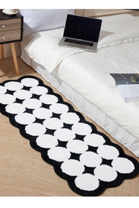 Close-up of black and white polka dot rug with wavy edges on light wood floor