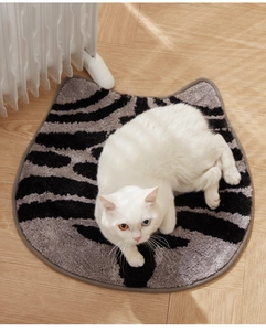 Close-up of cat-shaped plush rug with absorbent black and gray stripes on wooden floor