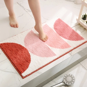 Absorbent bathroom rug with red geometric pattern shown on marble tile floor