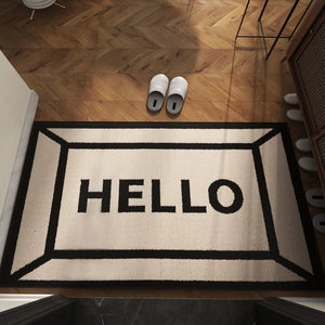Modern beige welcome mat with black HELLO text and geometric border on wood floor
