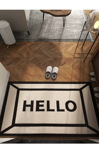Detail view of HELLO printed door mat on herringbone wood floor in modern home interior