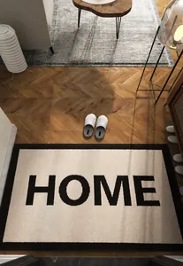 Primer plano de alfombra de entrada crema con borde negro y texto HOME estampado