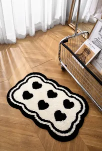 Detail van de zachte crèmekleurige badmat met zwarte hartjes en golvende randen