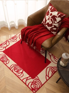 Detail shot of red New Year floor mat with rose floral borders on wooden floor
