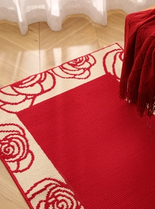 Detailed close-up of a festive red carpet with floral patterns on wooden flooring