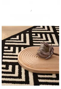 Detail of minimalist black and white geometric doormat with woven texture on wood floor