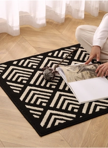 Macro detail of high-density knitted geometric V-pattern doormat on light wood floor