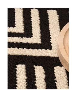 Detailed macro view of the thick tufted fiber texture on a black and white geometric doormat