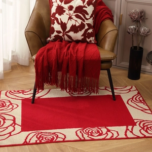Festive red rose patterned carpet with woven tassel blanket and matching pillow decor