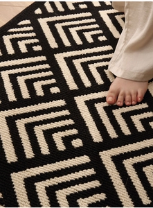 Detailed close-up of geometric tufted door mat showing black and white woven texture