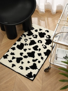 Detailed view of plush cow print rug on fishbone wood floor with modern black chair