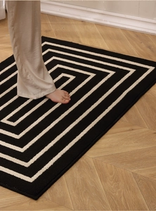 Close-up of geometric spiral pattern on a thick non-slip entry mat over wood floor