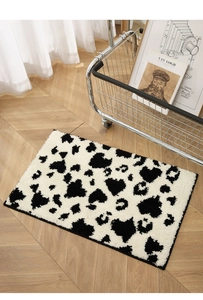 Detail of tufted cow heart pattern bathroom rug on a herringbone wood floor