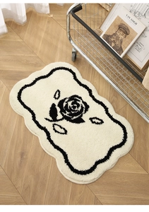 Detail van getufte rozenmat met golvende randen op visgraat houten vloer