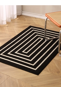 Detailed texture of black rectangular entryway mat with ivory geometric maze pattern