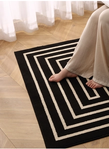 Close-up of minimalist black and white geometric maze pattern indoor entrance door mat