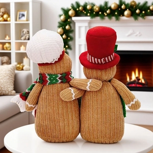 Knitted gingerbread man plush dolls hugging in a warm Christmas living room decor