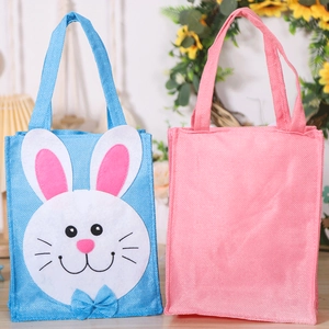 Détail de sacs cadeaux de Pâques en non-tissé avec motifs lapins sur une table en bois