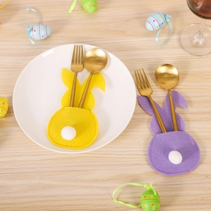 Easter bunny felt cutlery holders in yellow and purple with pom-pom tails on table