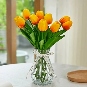 Close-up of orange faux tulip bouquet in a geometric glass vase with handmade ribbon