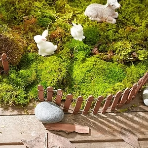 Miniature garden scene with bendable brown wooden fence and small white resin animals
