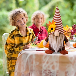 Dettaglio di gnomo autunnale di peluche con girasole su cappello a righe in giardino