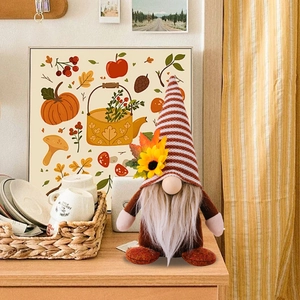 Dettaglio di gnomo autunnale in peluche con cappello a righe, girasole e foglia d'acero