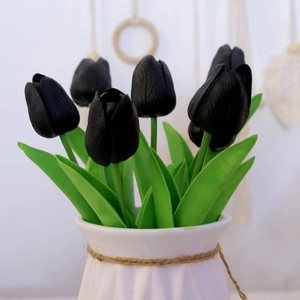 Realistic matte black artificial tulips in white ceramic vase with rustic hemp rope