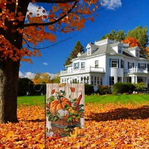 Detail of double-sided linen garden flag with autumn pumpkin and maple leaves in a yard