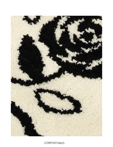 Detailopname van de dikke pluche badmat met zachte zwarte bloemmotieven en textuur