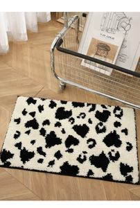 Close-up of soft black and white cow print rug with heart shapes on wooden floor